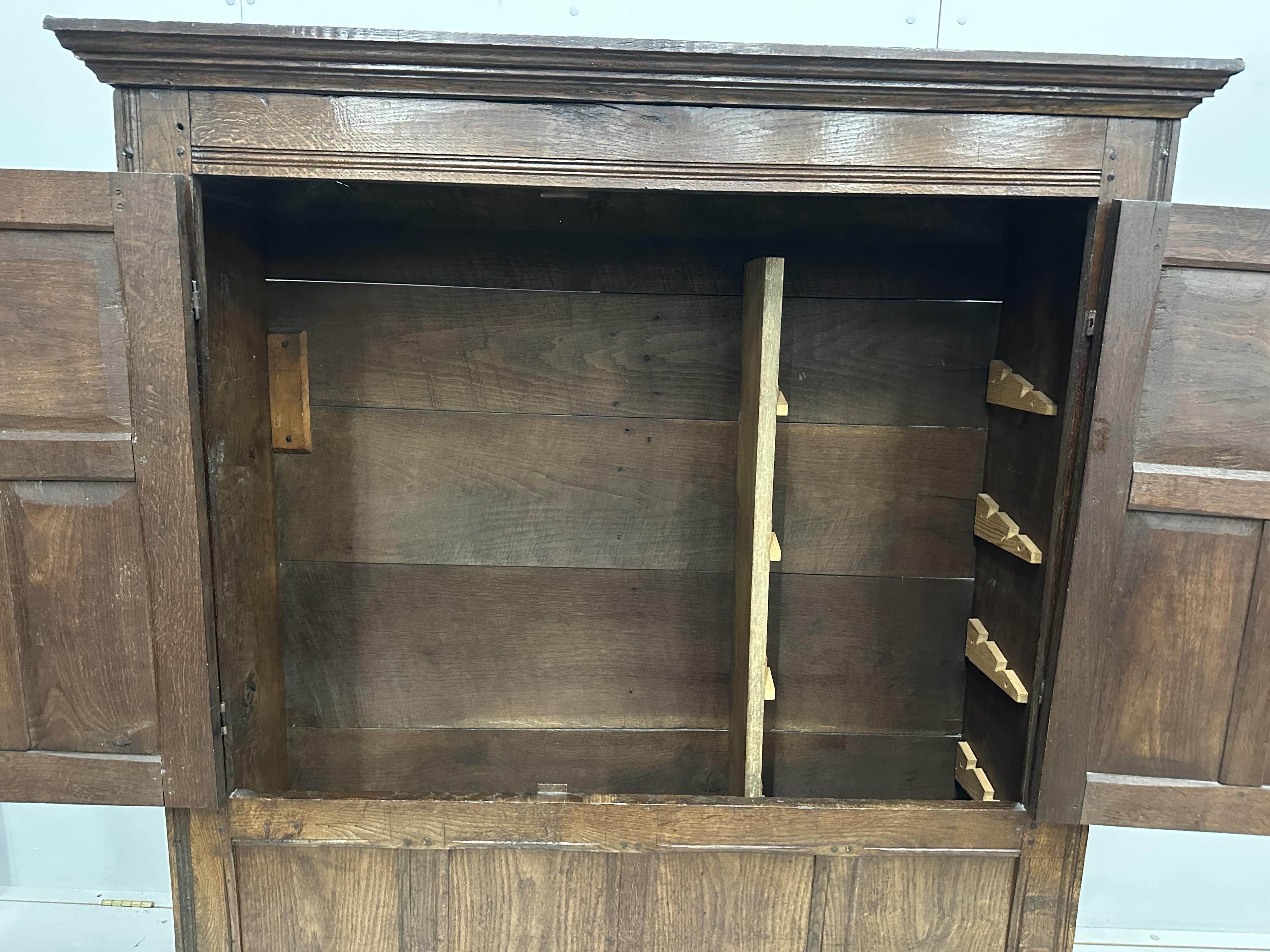 An 18th century and later panelled oak cupboard, width 140cm, height 159cm. Condition - good